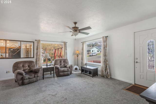 living room featuring baseboards, carpet flooring, a textured ceiling, and ceiling fan