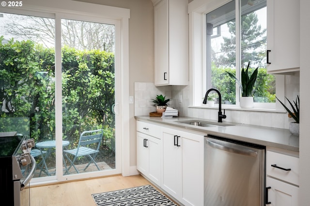 kitchen with sink, stainless steel appliances, white cabinetry, and plenty of natural light