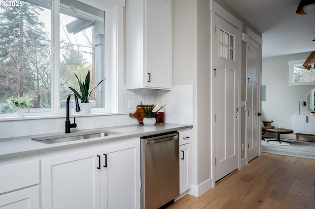 kitchen featuring white cabinetry, light wood-type flooring, dishwasher, and sink