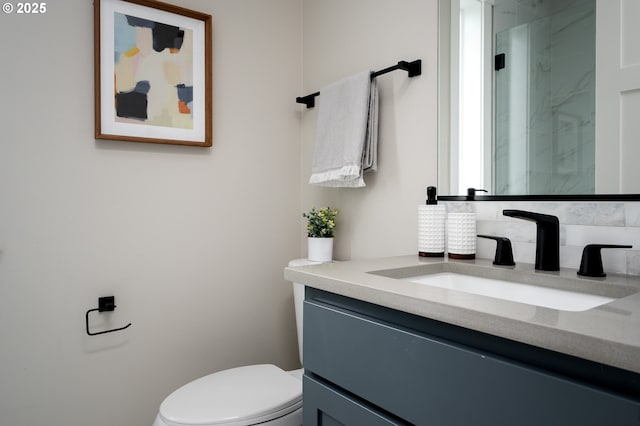 bathroom featuring toilet, vanity, and a shower with shower door