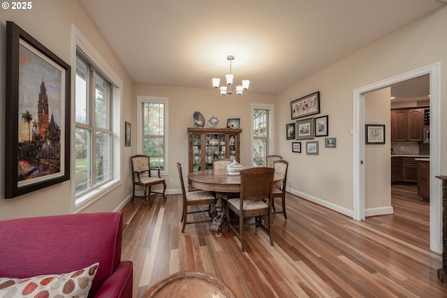 dining room featuring a chandelier, light wood-type flooring, and baseboards