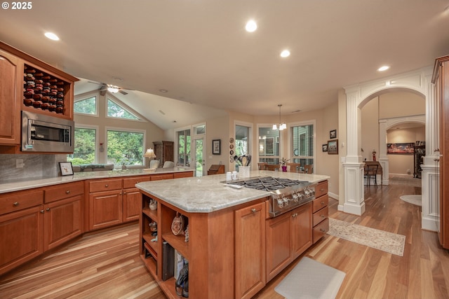 kitchen featuring arched walkways, a ceiling fan, open shelves, a center island, and stainless steel appliances