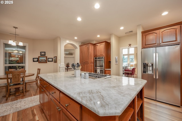 kitchen featuring light wood-style floors, recessed lighting, stainless steel appliances, a kitchen island, and light stone counters