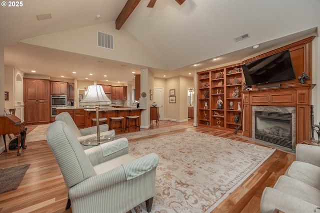 living area with light wood-style floors, high vaulted ceiling, beamed ceiling, and visible vents