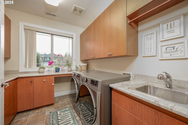 washroom featuring visible vents, washer and dryer, a sink, cabinet space, and stone finish flooring