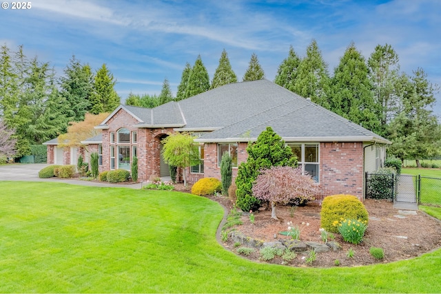view of front of house with a shingled roof, fence, brick siding, a front lawn, and a gate