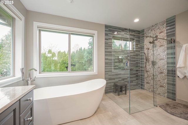bathroom with a shower stall, a freestanding tub, vanity, and recessed lighting