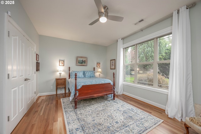 bedroom with light wood-style floors, baseboards, a ceiling fan, and visible vents