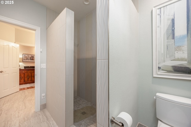bathroom with toilet, tiled shower, marble finish floor, and connected bathroom