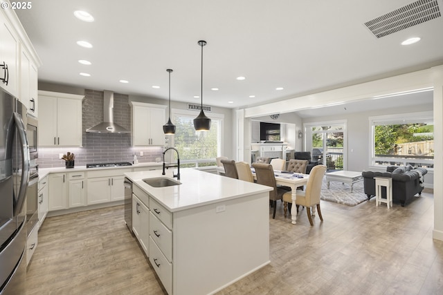 16290 SE Eckert Ln, Damascus, OR 97089 - kitchen featuring wall chimney exhaust hood, open floor plan, light wood finished floors, light countertops, and white cabinets
