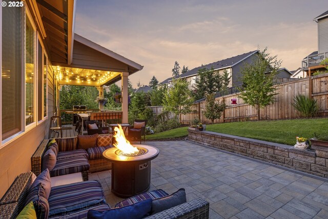 16290 SE Eckert Ln, Damascus, OR 97089 - patio terrace at dusk featuring a patio, a fenced backyard, and an outdoor living space with a fire pit