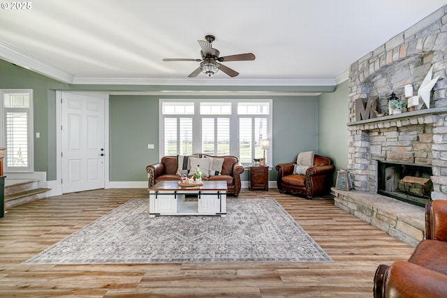 living room with ceiling fan, ornamental molding, a fireplace, and light hardwood / wood-style flooring