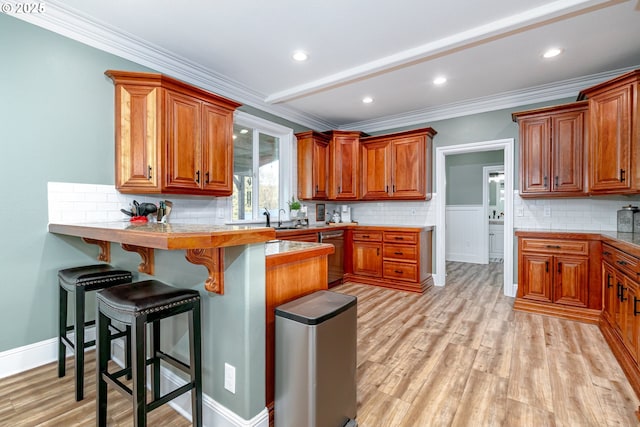 kitchen featuring dishwasher, crown molding, a breakfast bar, and light wood-type flooring