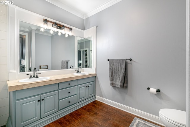 bathroom featuring vanity, hardwood / wood-style flooring, ornamental molding, and toilet