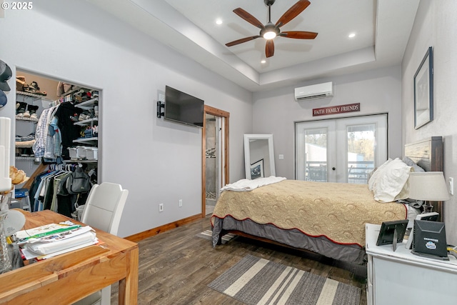 bedroom featuring dark wood-type flooring, ceiling fan, access to exterior, a wall unit AC, and a tray ceiling