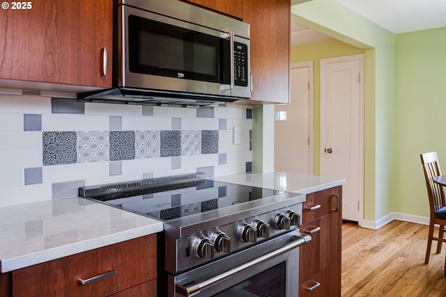 2445 SE 76th Ave, Portland, OR 97206 - kitchen featuring stainless steel appliances, decorative backsplash, light wood-type flooring, baseboards, and brown cabinetry