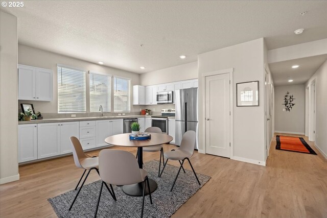 dining room featuring light wood-style flooring, baseboards, recessed lighting, and a textured ceiling