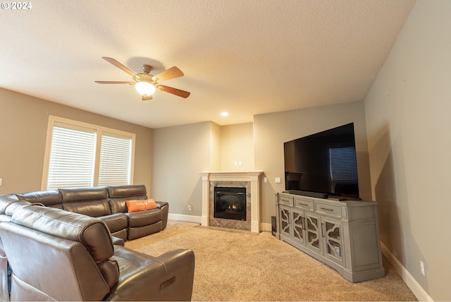 living room featuring ceiling fan, light colored carpet, a fireplace, and a textured ceiling