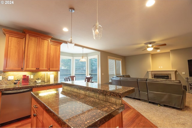 kitchen featuring tasteful backsplash, decorative light fixtures, dishwasher, a kitchen island, and a fireplace