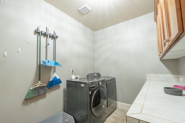 laundry room featuring washer and clothes dryer, cabinets, and a textured ceiling