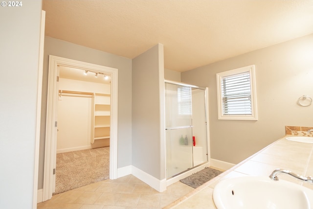 bathroom with vanity, a shower with shower door, tile patterned flooring, and a textured ceiling