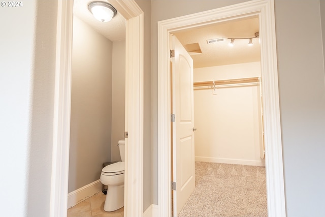 bathroom featuring toilet, tile patterned flooring, and a textured ceiling