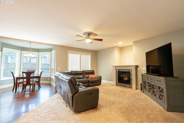 living room with a textured ceiling, a fireplace, ceiling fan, and hardwood / wood-style flooring