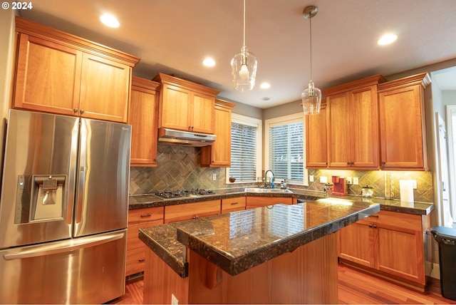 kitchen with pendant lighting, sink, light hardwood / wood-style flooring, appliances with stainless steel finishes, and a center island