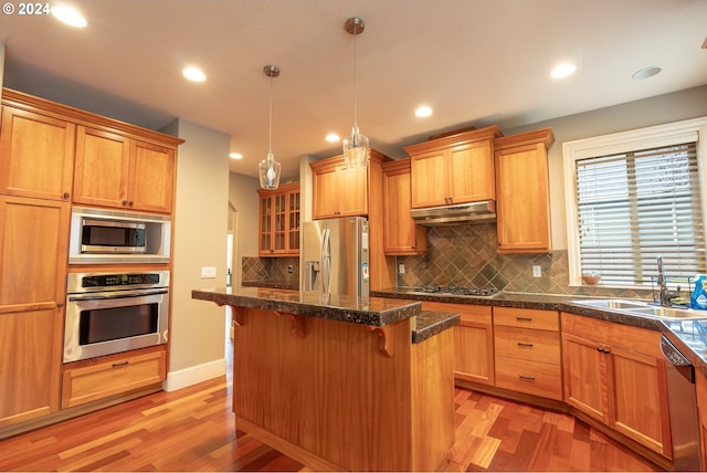 kitchen featuring pendant lighting, sink, a breakfast bar area, appliances with stainless steel finishes, and a center island