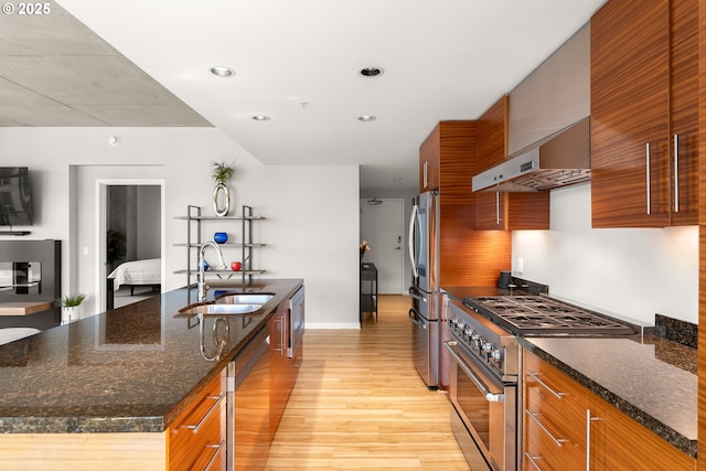 1830 NW Riverscape St Unit 406, Portland, OR 97209 - kitchen with wall chimney range hood, a kitchen island with sink, a sink, light wood finished floors, and stainless steel appliances