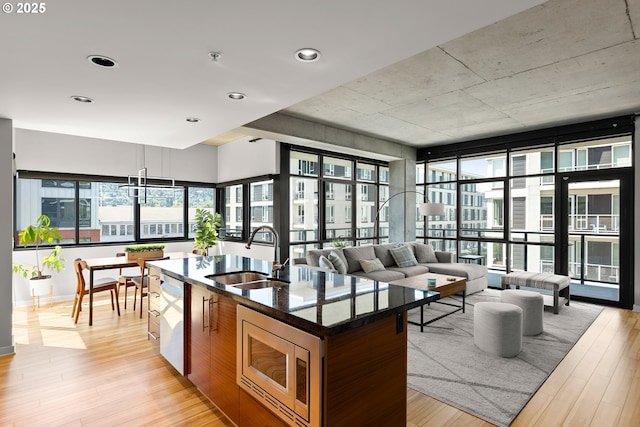 1830 NW Riverscape St Unit 406, Portland, OR 97209 - kitchen with a kitchen island with sink, open floor plan, a sink, light wood-style flooring, and appliances with stainless steel finishes