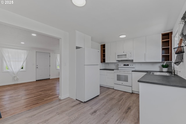 kitchen with a sink, white appliances, open shelves, white cabinets, and dark countertops
