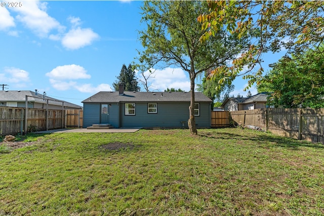 back of property featuring a fenced backyard, a patio area, a chimney, and a lawn