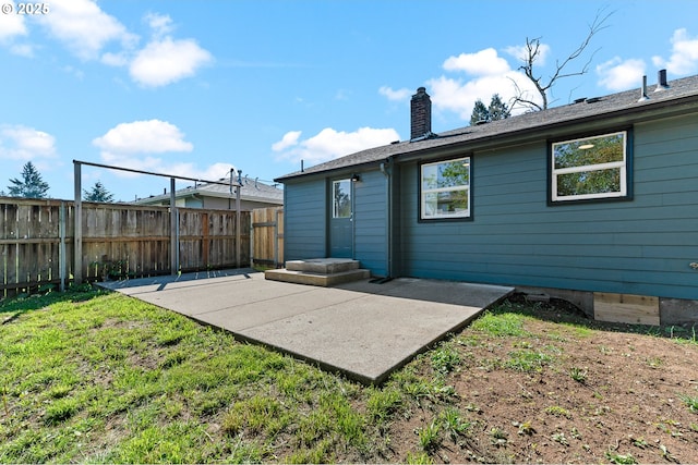 back of house with a yard, a patio area, a chimney, and fence