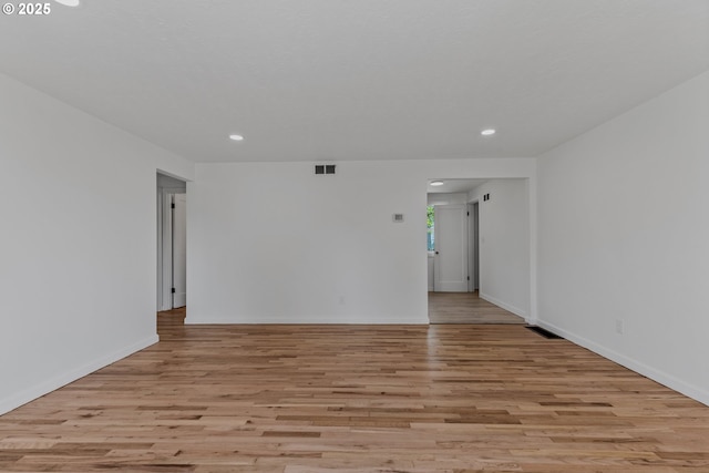 empty room featuring visible vents, wood finished floors, baseboards, and recessed lighting