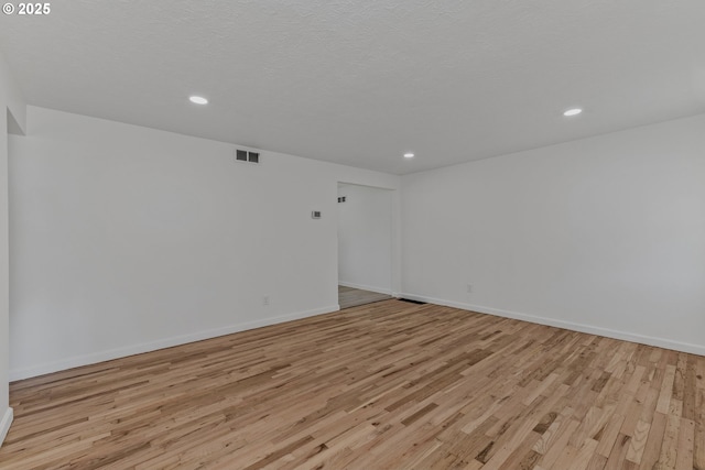 spare room featuring light wood finished floors, baseboards, visible vents, and recessed lighting