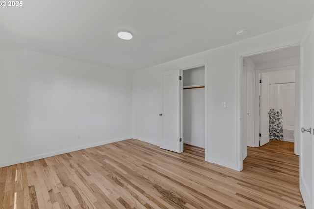 unfurnished bedroom with light wood finished floors, baseboards, and a closet