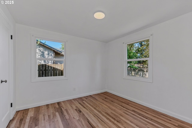 spare room featuring a wealth of natural light, baseboards, and light wood-type flooring