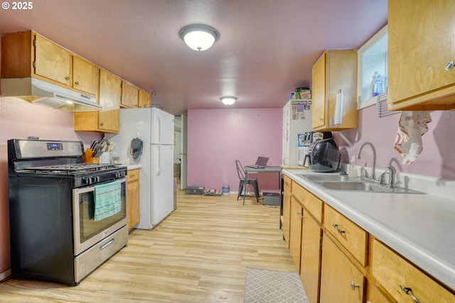 kitchen featuring gas range, white fridge, sink, and light wood-type flooring