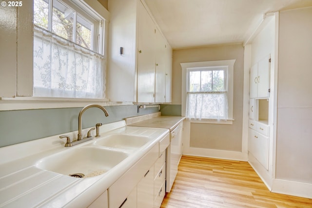 1206 E 9th St, The Dalles, OR 97058 - kitchen with baseboards, white dishwasher, light countertops, a sink, and light wood finished floors
