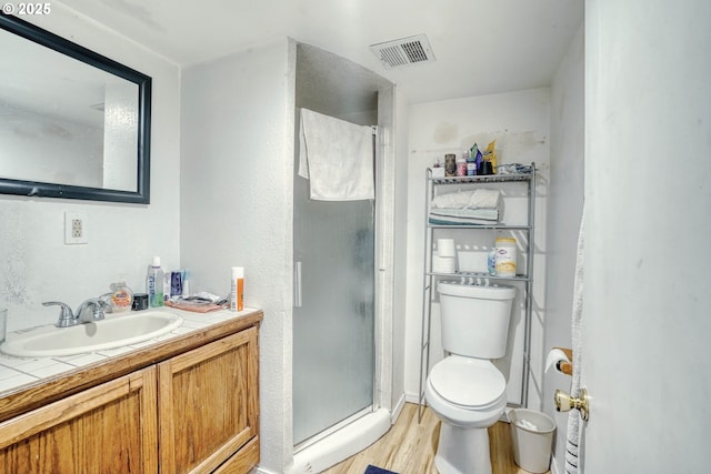 bathroom with vanity, toilet, a shower with shower door, and hardwood / wood-style floors