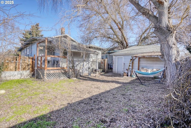 back of house with a wooden deck, a garage, and an outdoor structure