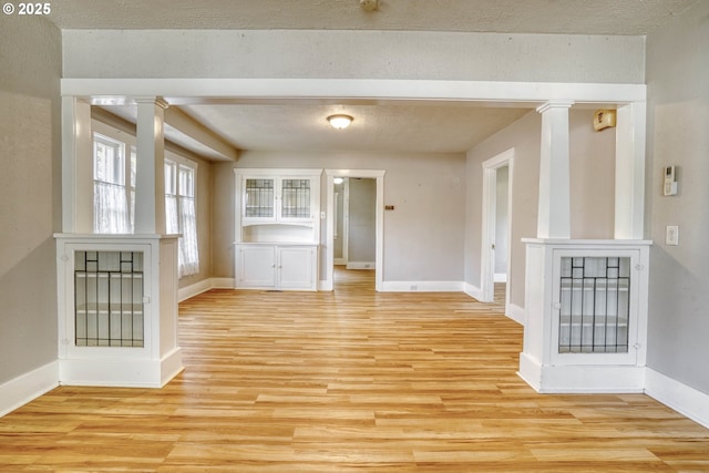 1206 E 9th St, The Dalles, OR 97058 - unfurnished dining area with baseboards, decorative columns, and light wood-style floors