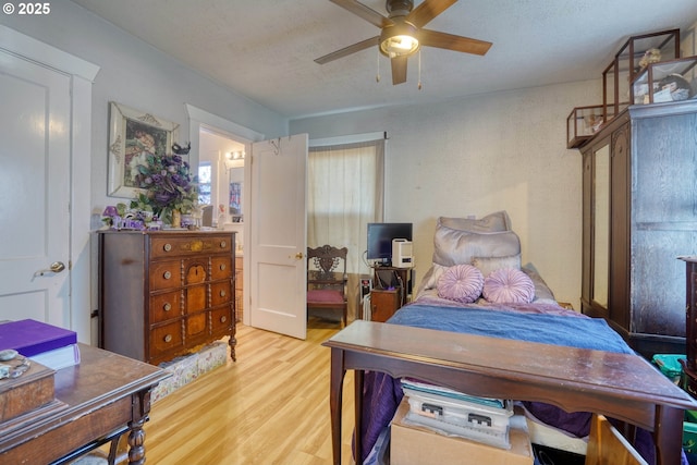 bedroom with ceiling fan, a textured ceiling, and light wood-type flooring