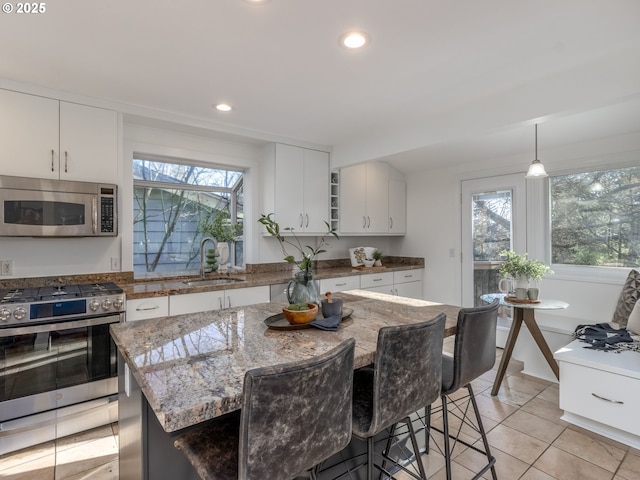 kitchen featuring pendant lighting, sink, stainless steel appliances, white cabinets, and a kitchen island