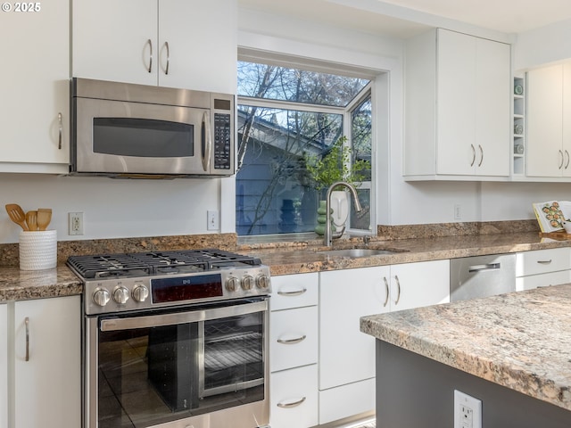 kitchen with light stone counters, sink, stainless steel appliances, and white cabinets