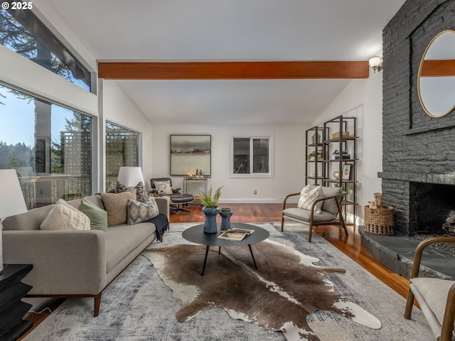 living room featuring a stone fireplace, vaulted ceiling with beams, and hardwood / wood-style floors