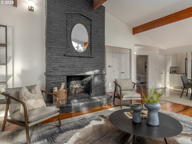 living room with hardwood / wood-style flooring, a stone fireplace, high vaulted ceiling, and beamed ceiling