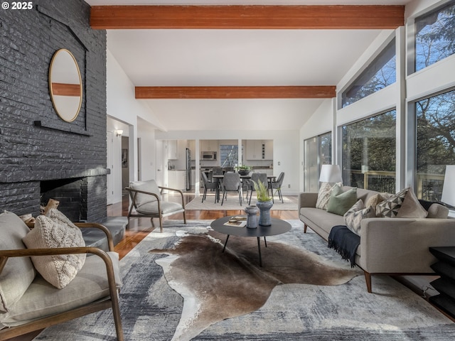 living room featuring beamed ceiling, a large fireplace, wood-type flooring, and high vaulted ceiling