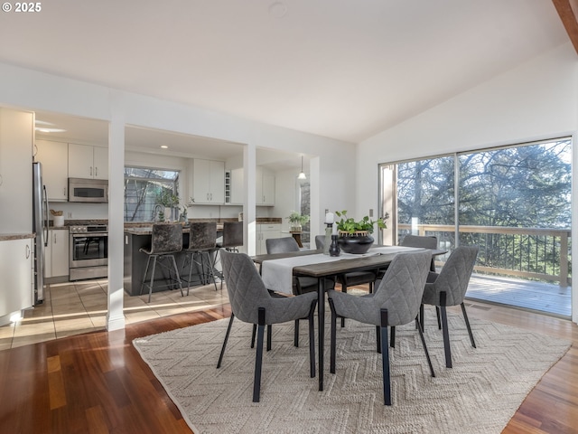 dining room with vaulted ceiling and light hardwood / wood-style floors